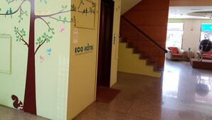 A hotel lobby with a tree mural, a staircase, and a sofa. - Gueylin Hotel (Taoyuan City)