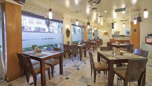 A restaurant interior with tiled flooring, wooden tables and chairs, pendant lighting, and a view of the street outside. - Gueylin Hotel (Taoyuan City)