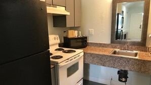 A compact kitchen with a black refrigerator, white stove, and a microwave. - Crown Inn Humble (Humble)