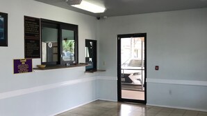 A hotel lobby with a chandelier, a reception desk, and a signboard with rules and check-in times. - Crown Inn Humble (Humble)