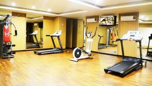 Une salle de sport équipée de tapis de course, d’un vélo elliptique et d’un vélo d’appartement.
