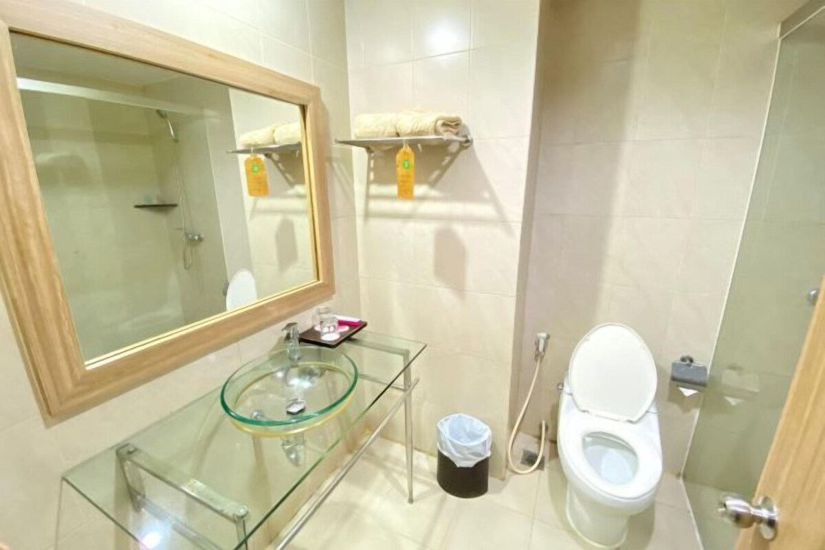 A bathroom with a glass sink, a toilet, a shower, and a towel rack.