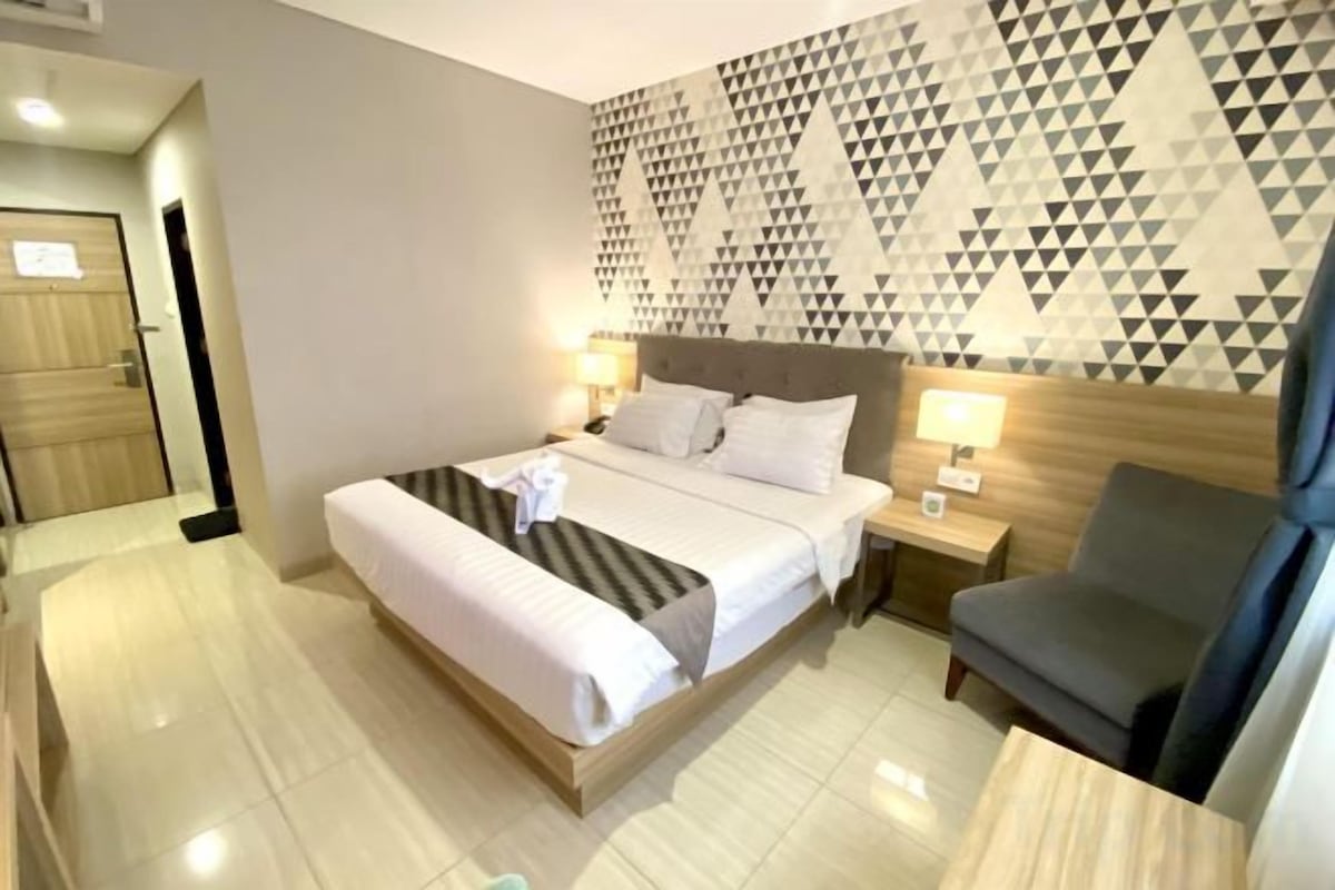 Ein Hotelzimmer mit einem Bett, Nachttischen, einem Sessel und einem geometrischen Wandmuster.