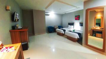 A hotel room with a bed, bedside table, chair, and a desk with a chair.