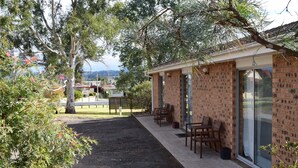 A brick building with a patio area featuring outdoor seating and a view of the surrounding landscape. - Bega Caravan Park (Bega)
