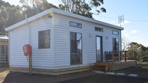 A white mobile home with a porch and a small deck. - Bega Caravan Park (Bega)