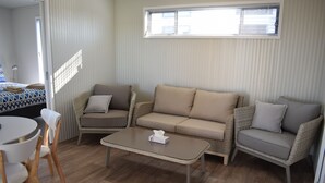 A room with a sofa set, a small table, and a chair. - Bega Caravan Park (Bega)