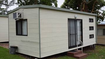 A single-story mobile home with a front door, a small porch, and a window.