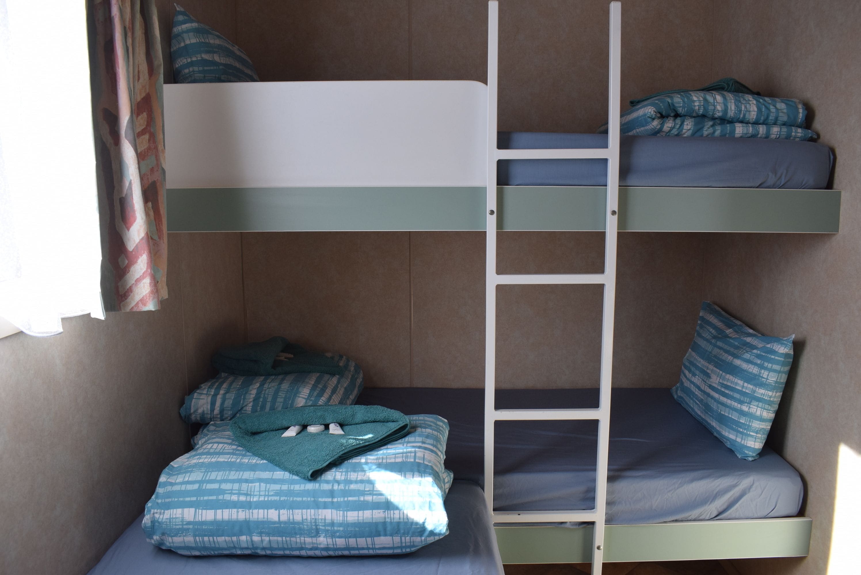 Habitación con literas, una escalera, dos camas y almohadas.