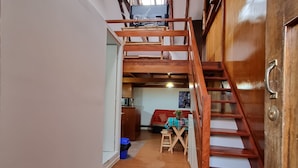 A wooden staircase leading to an upper level with a TV mounted on the wall. - Hospedaje Laura (Cusco)