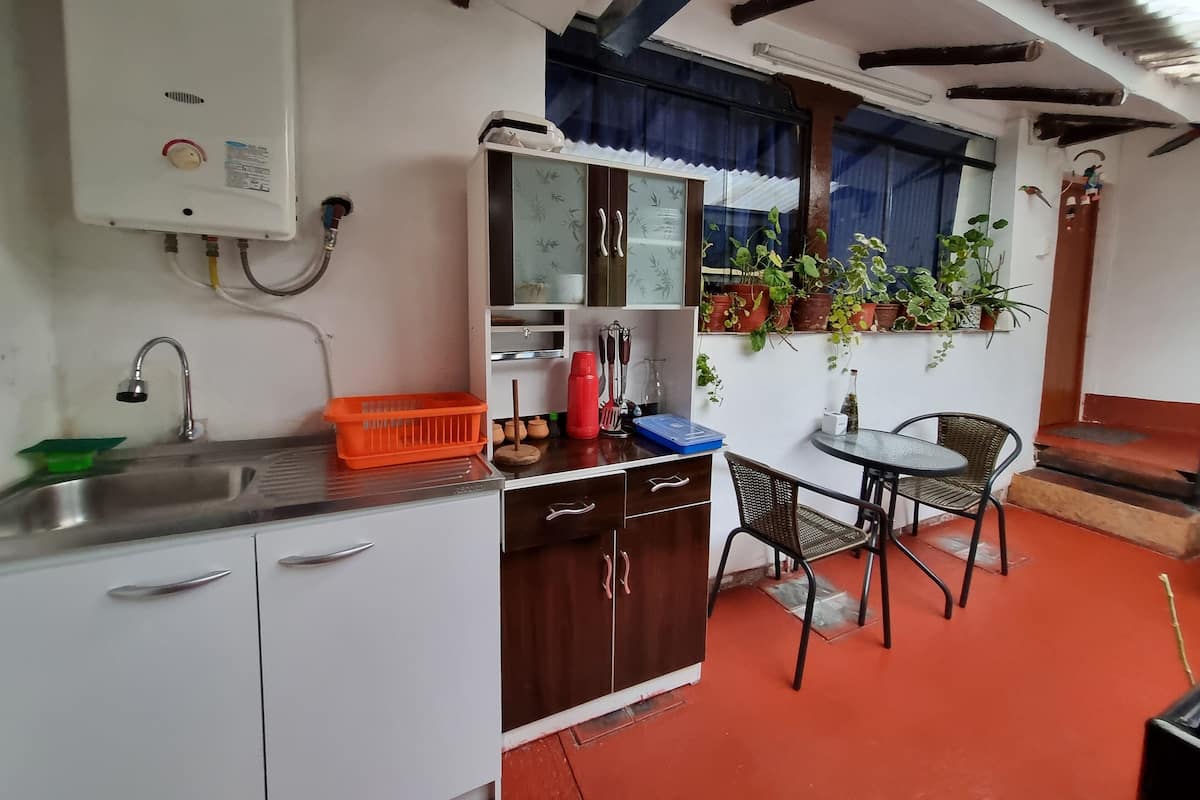 A compact kitchen with a sink, cabinets, and a dining area with chairs.