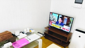 Een moderne woonkamer met een flatscreen televisie, een witte bank, een glazen salontafel en een witte luchtreiniger.