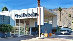 The exterior of the Ocottillo Lodge with a clear view of the entrance, palm trees, and a mountainous backdrop. - Mid-Century Modern Bohemian Bungalow w/ Pool (Palm Springs)