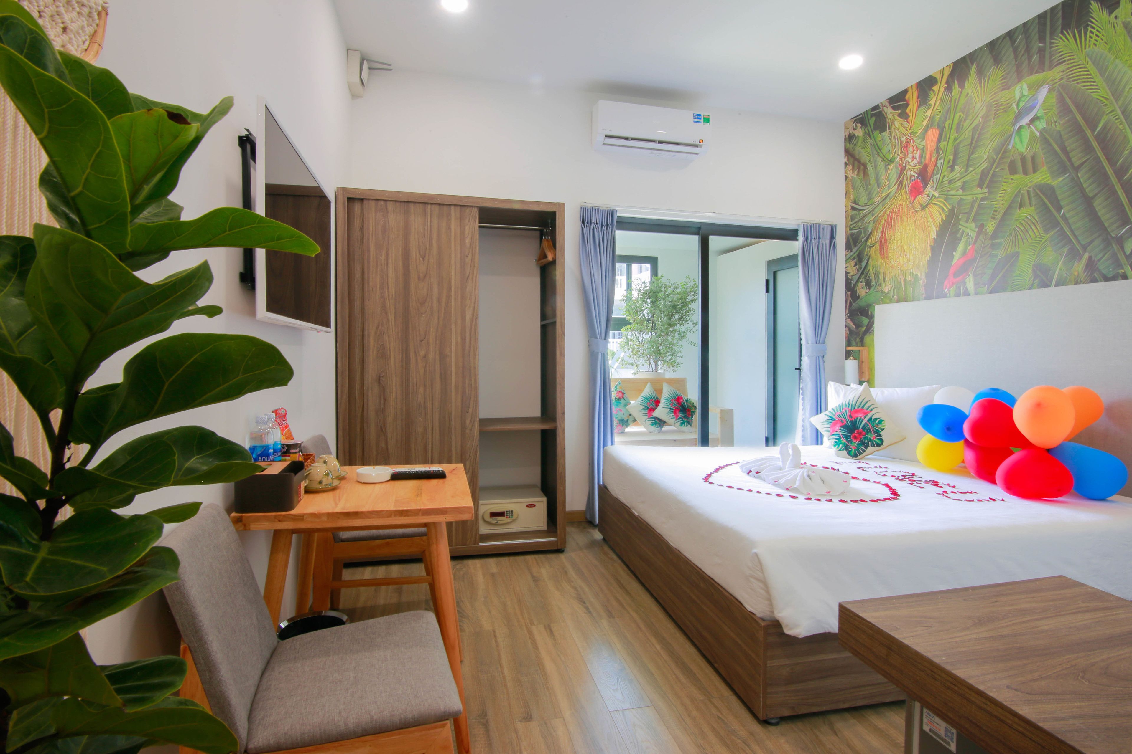 Una habitación de hotel con cama, escritorio, silla, armario y un ventanal grande.
