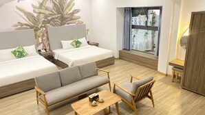 Una habitación de hotel moderna con dos camas, un sofá, una mesita y una ventana con cortinas.