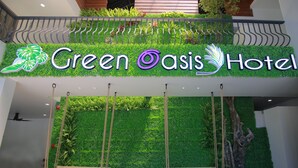 Señal del Hotel Green Oasis, con una pared verde exuberante y dos columpios al frente.