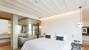 A modern bedroom with a large bed, a glass shower enclosure, and a wooden nightstand with a clock. - SYN Boutique Hotel (Chiang Mai)