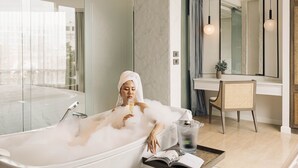 A woman in a bathtub filled with bubbles, a book, and a glass of wine on a side table. - SYN Boutique Hotel (Chiang Mai)