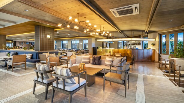 A spacious lobby with modern furniture, a central coffee bar, and large windows offering views. - SYN Boutique Hotel (Chiang Mai)
