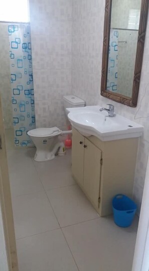 A small bathroom with a toilet, sink, and mirror.