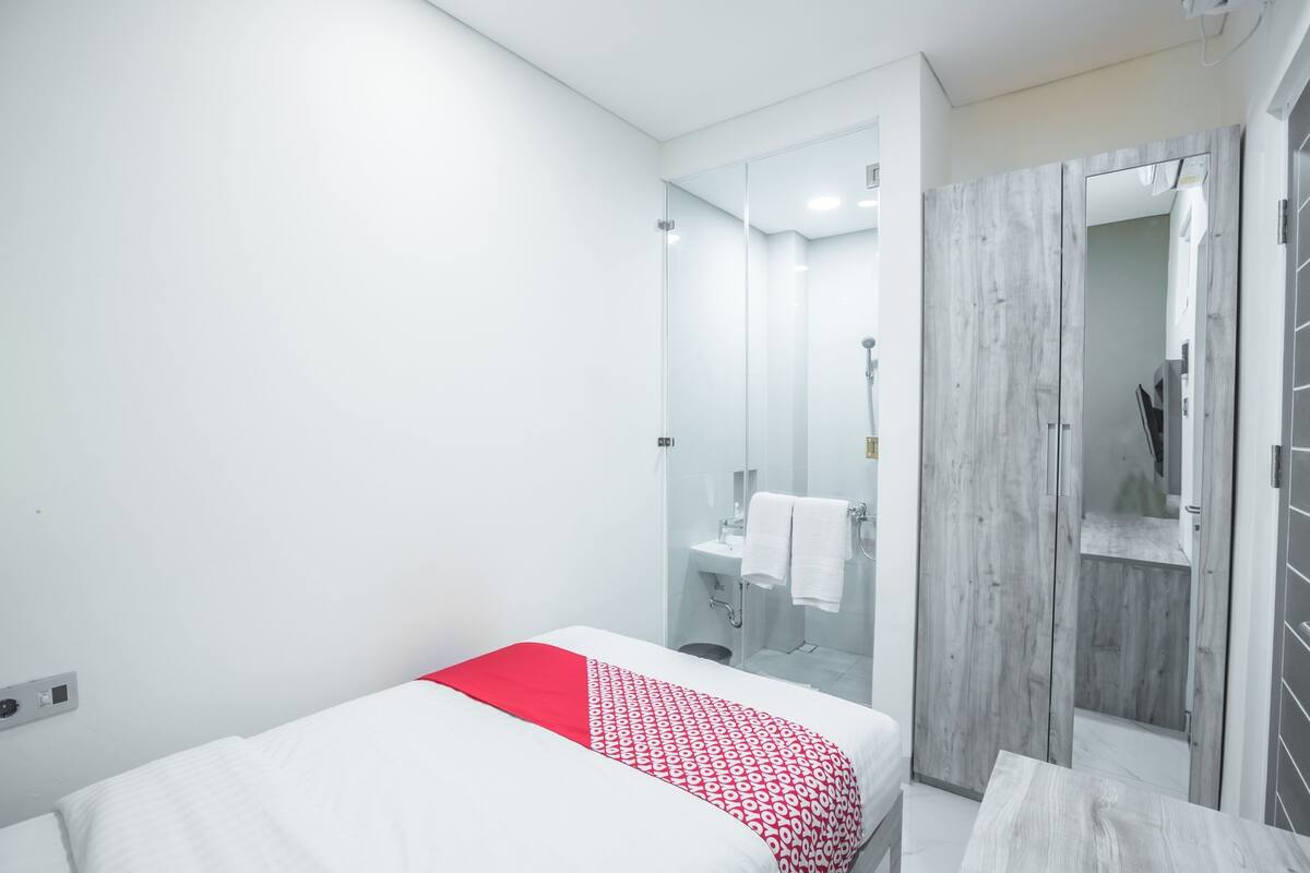 Ein modernes Hotelzimmer mit Bett, Dusche, Waschtisch und Kleiderschrank.