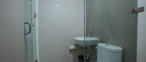 Un baño con cabina de ducha de vidrio, un lavabo blanco y un inodoro.