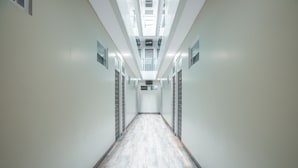 A long, narrow hallway with a light-colored floor and white walls, leading to a door at the end. - Hotel O Residence Khoe (Jakarta)