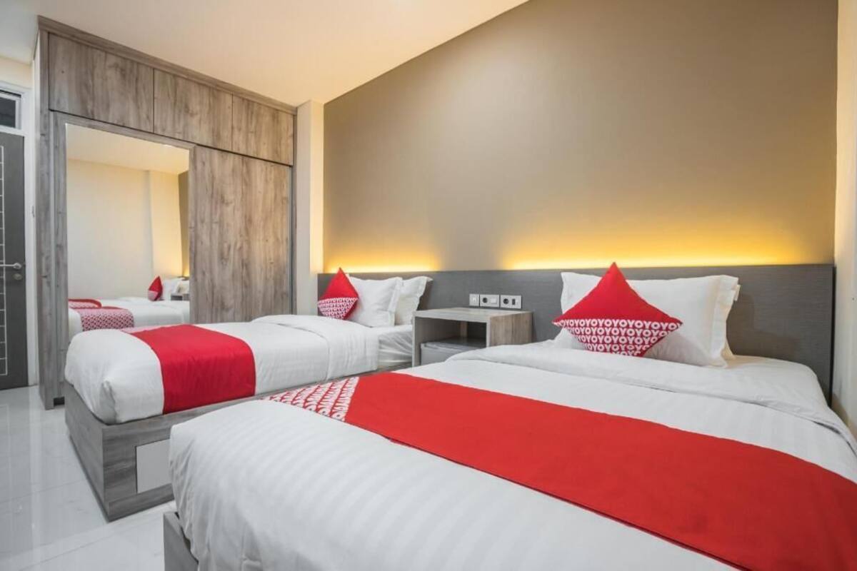 Ein Hotelzimmer mit zwei Betten, einem Kleiderschrank, einem Nachttisch und einem Spiegel.