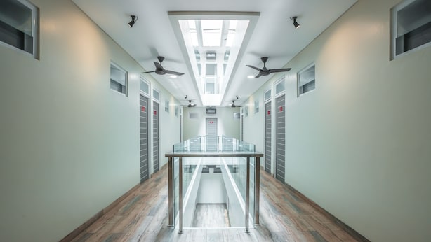 A modern hallway with a glass table, ceiling fans, and a skylight. - Hotel O Residence Khoe (Jakarta)