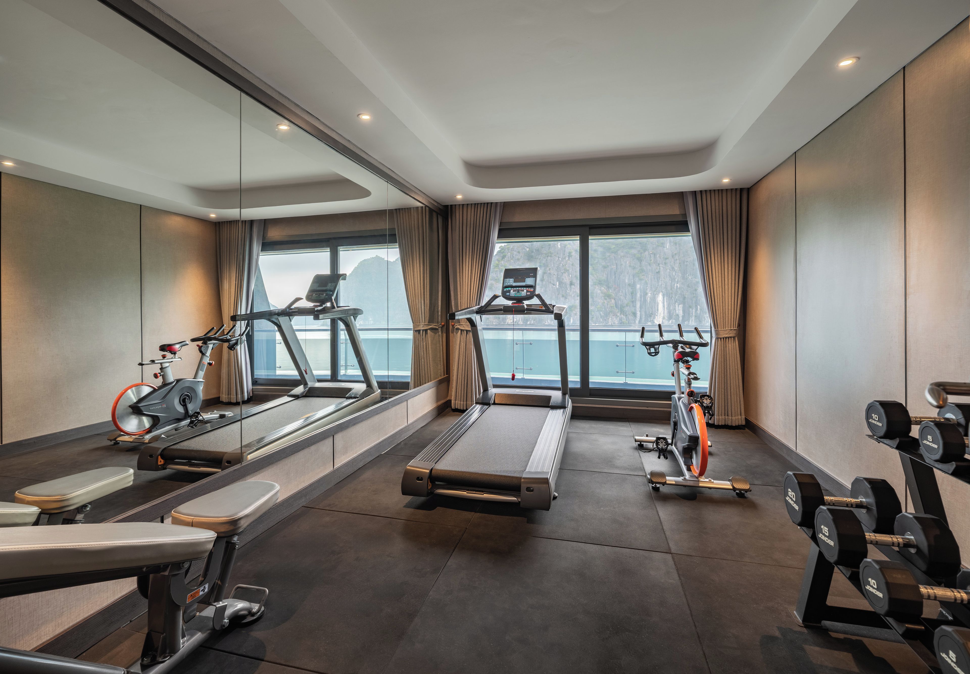 A gym with cardio equipment, weight machines, and dumbbells.