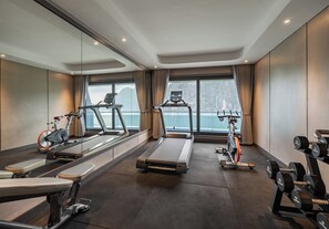 Un gimnasio con equipo cardiovascular, máquinas de pesas y mancuernas.
