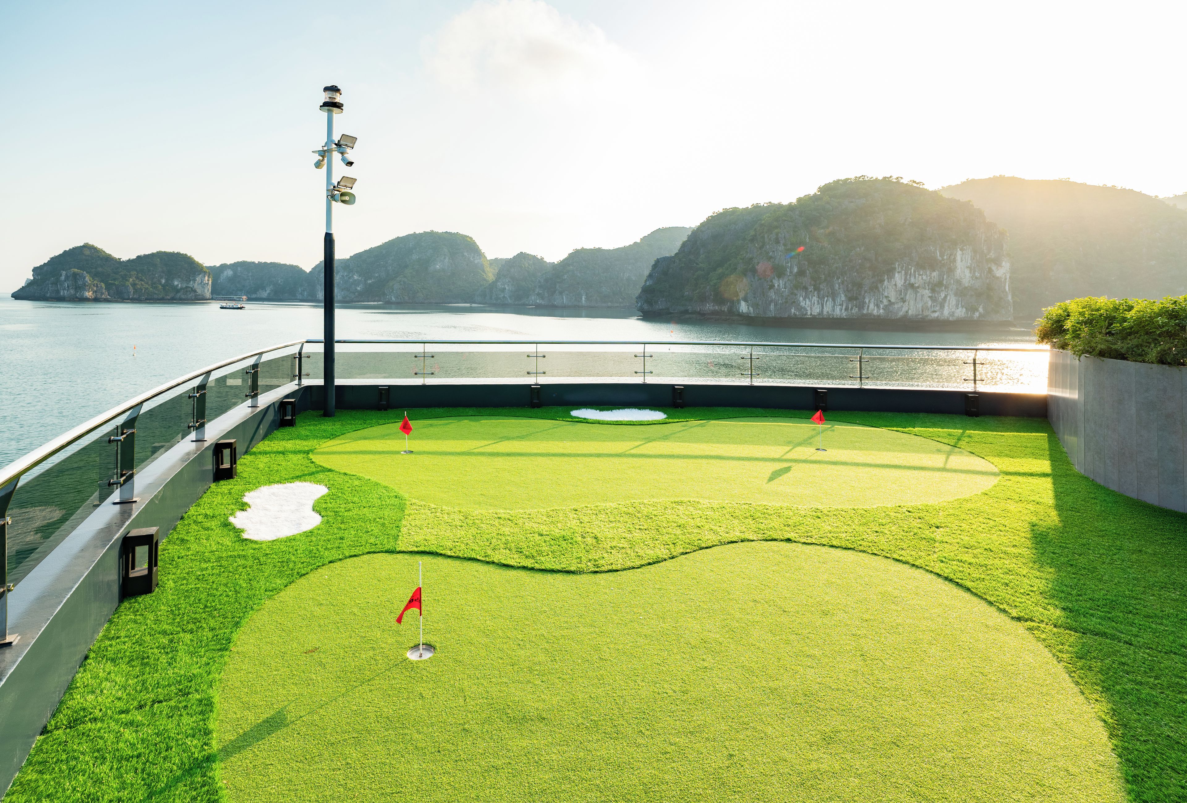A golf course with a flag, water, and distant mountains.