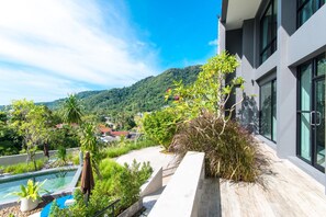 A modern building with a pool, surrounded by lush greenery and a mountainous backdrop. - Modern Property Nearby Kamala Beach W Pool (Kamala)