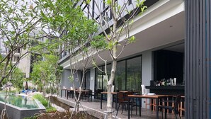 Uma área moderna para refeições ao ar livre, com mesas, cadeiras, piscina e bar.