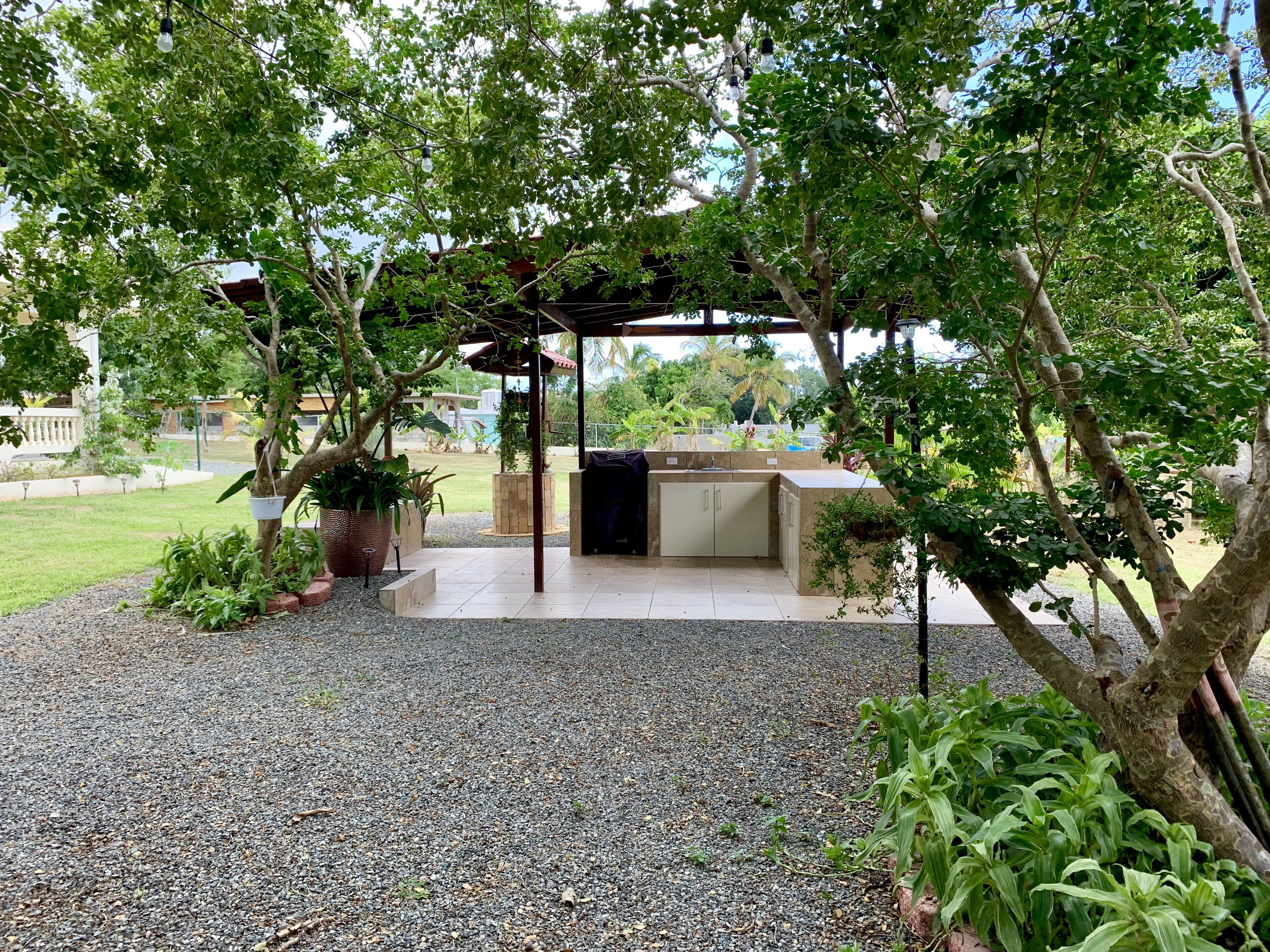 An outdoor patio area with a pergola, a barbecue grill, and a built-in kitchen counter.
