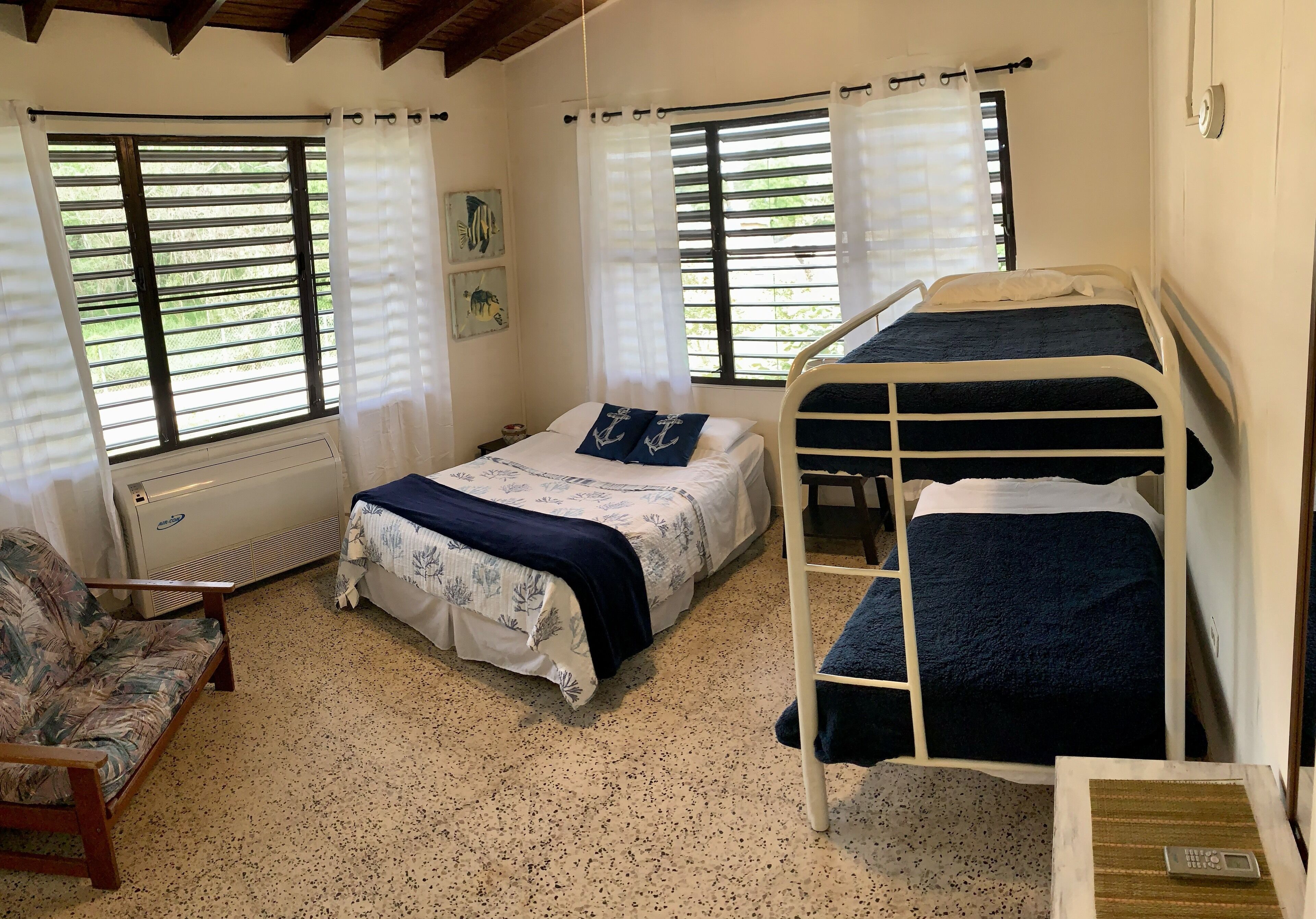 A bedroom with two beds, a chair, and a window with blinds.