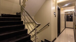 A modern hotel interior with a staircase, a sign indicating the floor level, and a clean, polished floor. - Hotel Atlas Grand (Mumbai)