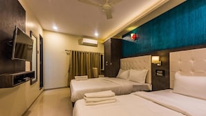 A hotel room with two beds, a flat-screen TV mounted on the wall, a ceiling fan, and a window with curtains. - Hotel Atlas Grand (Mumbai)