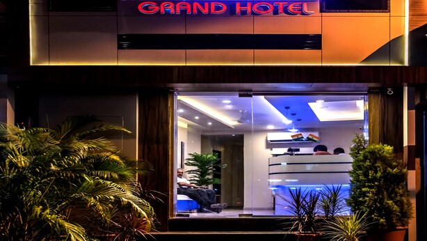 The exterior of the Atlas Grand Hotel with a prominent illuminated sign, a modern facade, and a welcoming entrance with potted plants. - Hotel Atlas Grand (Mumbai)