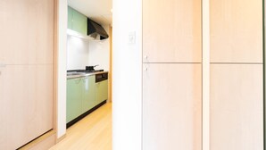 A modern kitchen with green cabinets, a black range hood, and a dishwasher. - Shinsaibash East Nana Apartment · Junan (Osaka)