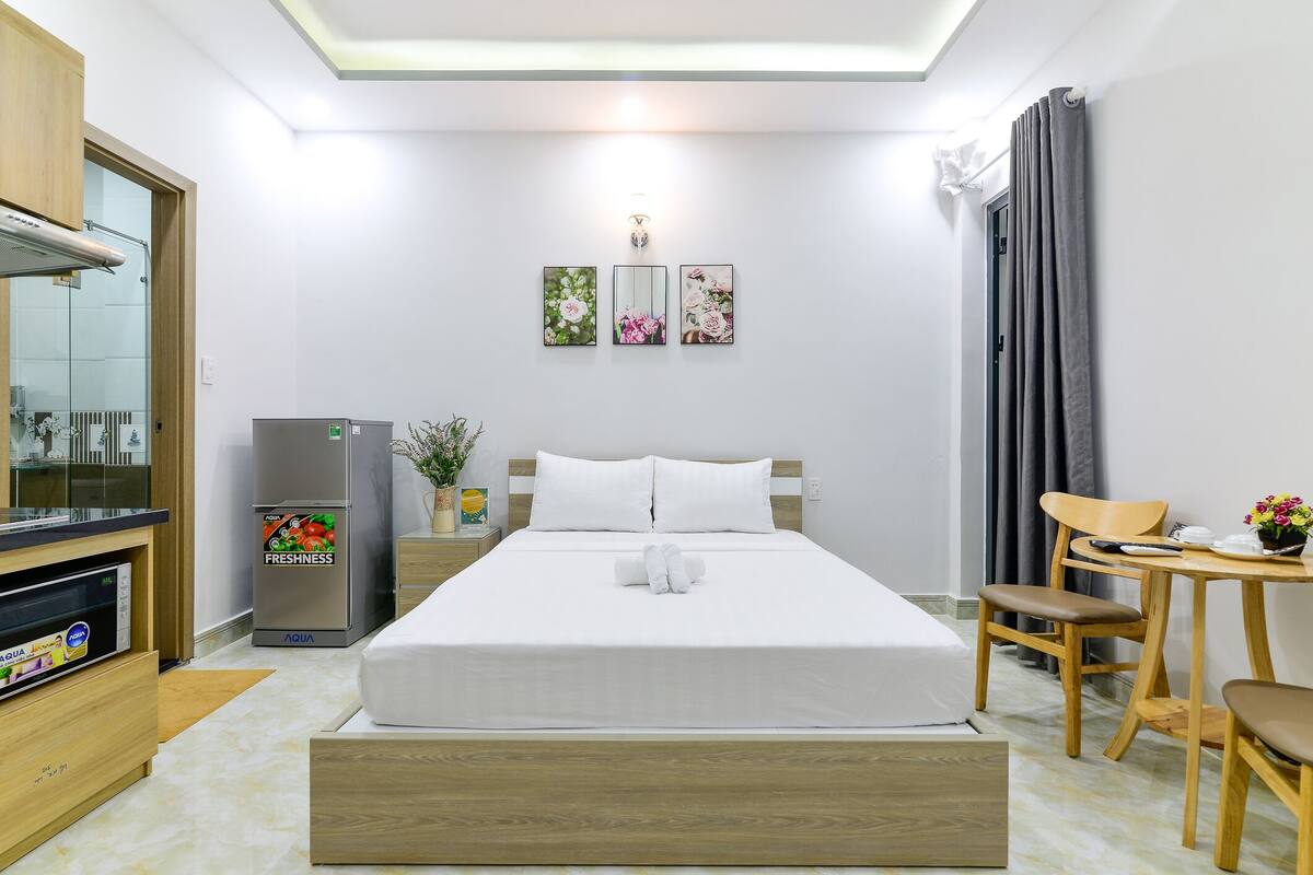 Une chambre d’hôtel équipée d’un lit, d’un bureau, d’une chaise, d’un réfrigérateur et d’un miroir.