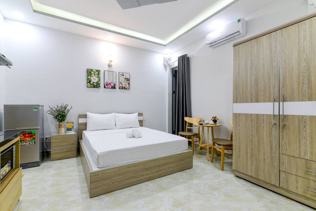 Une chambre d’hôtel moderne avec un lit en bois, un bureau, une armoire et un téléviseur.