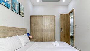 Una habitación de hotel con cabecera de madera, una cama grande con sábanas blancas, un armario de madera y una puerta de madera.