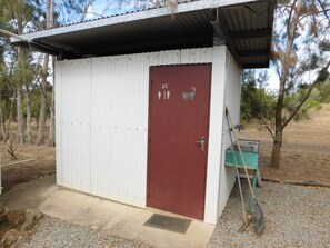 Um pequeno edifício térreo com porta vermelha, fachada branca e telhado de metal.