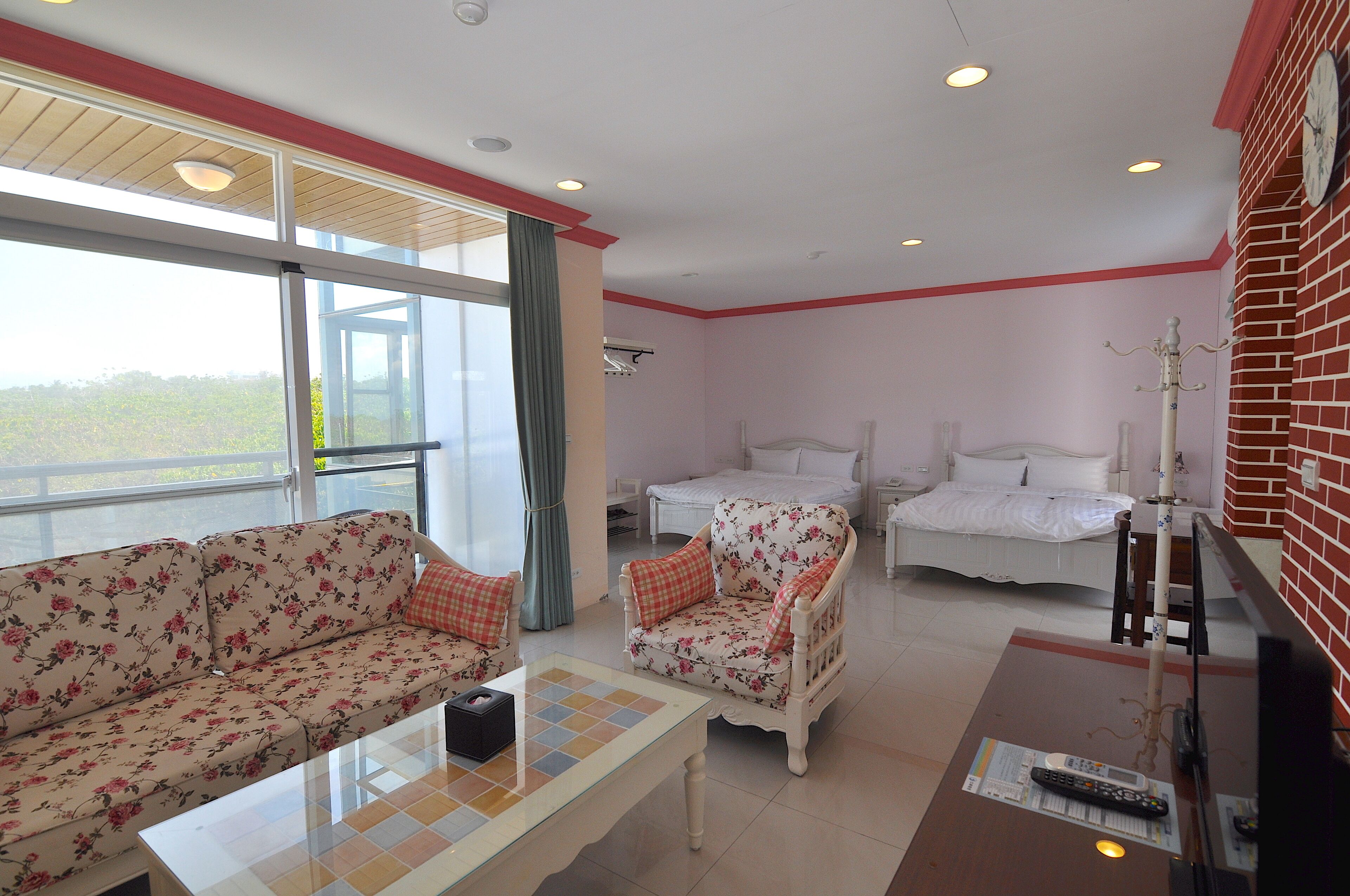 A hotel room with a sofa, armchair, and two beds.