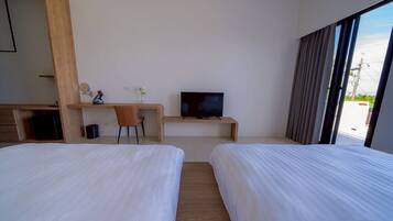 A hotel room with two beds, a desk with a television, a chair, and a window with curtains.