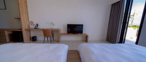 Habitación de hotel con dos camas, un escritorio con televisor, una silla y una ventana con cortinas.