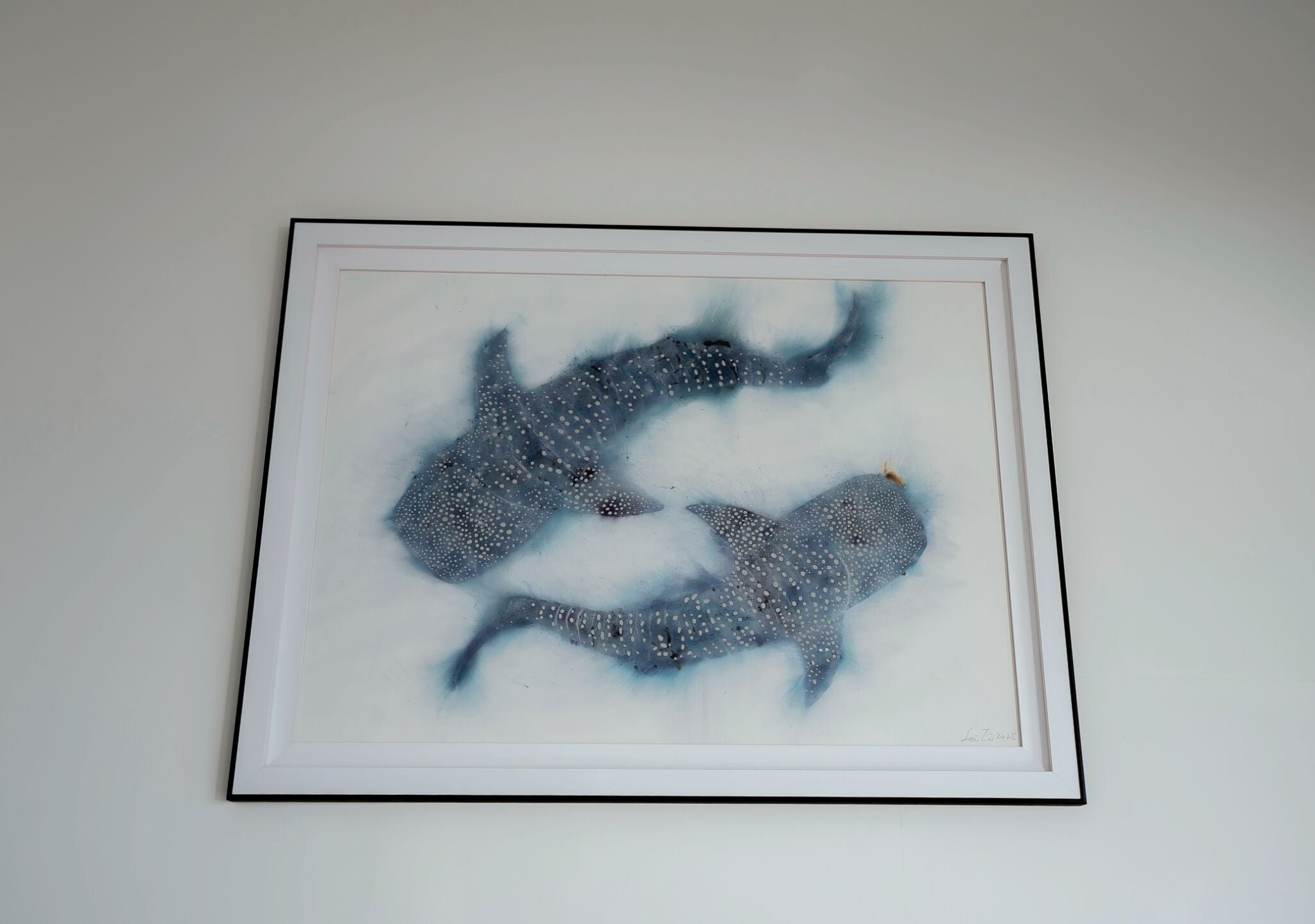 Obra de arte enmarco con dos ballenas sobre una pared blanca.