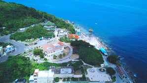 An aerial view of a coastal town with a central building complex, a beach, and a road network. - Star Sea B&B (Liuqiu)