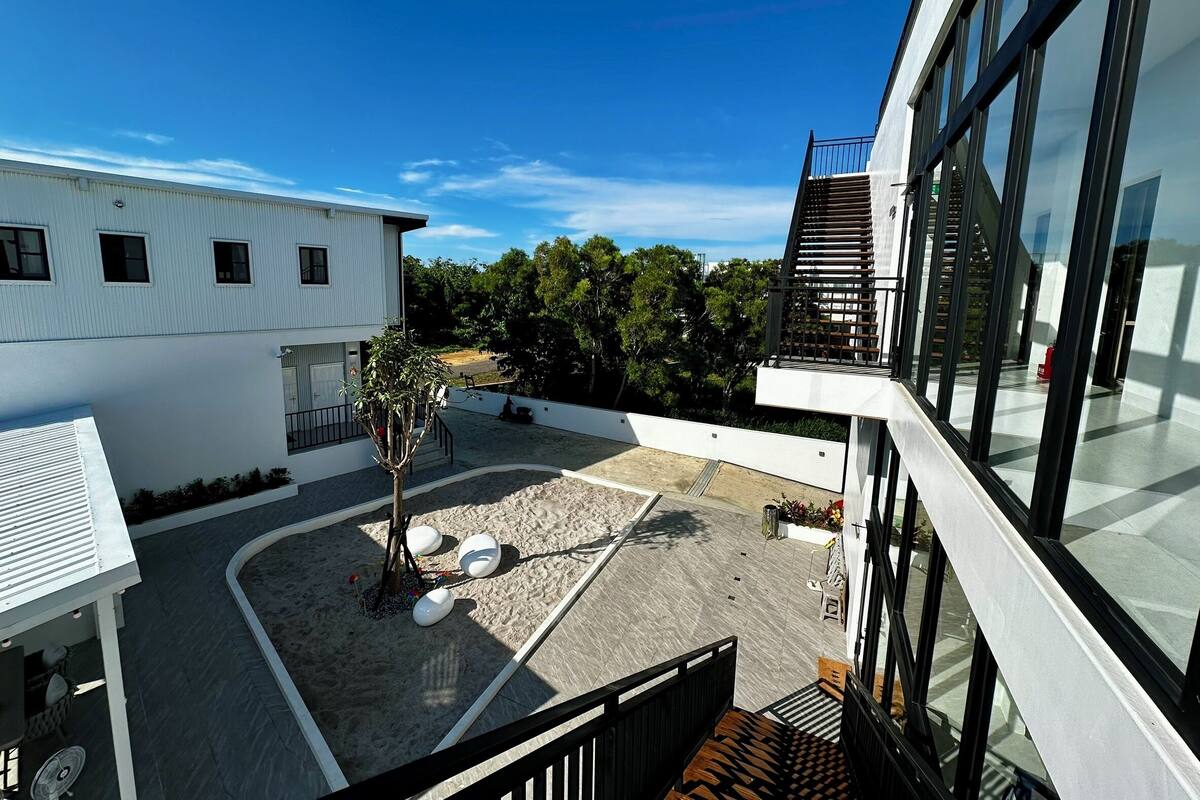 A modern building with a rooftop patio area, a staircase, and a view of the surrounding greenery.